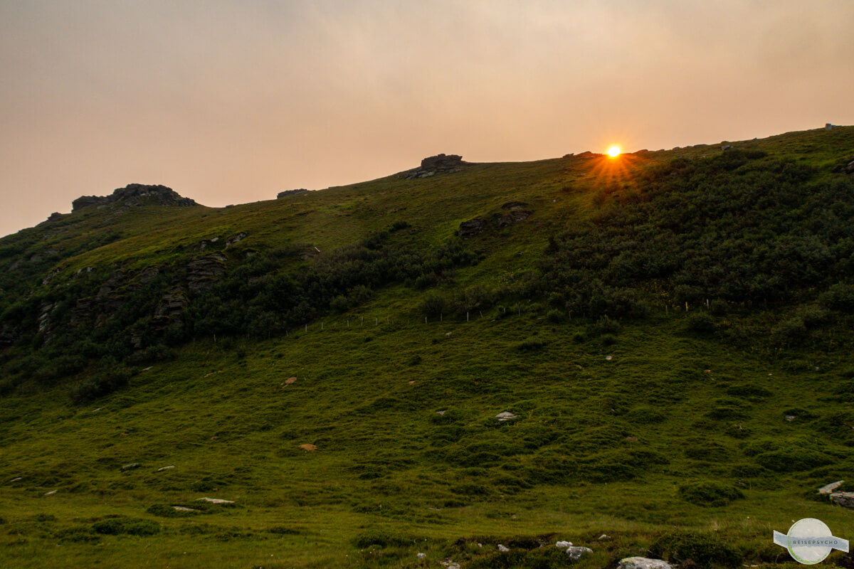 Sonne kommt hinter einer Bergkuppe hervor