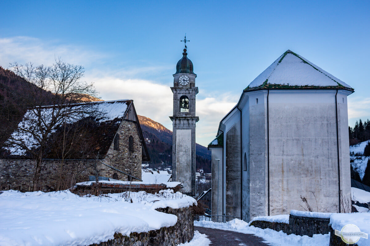 Kirche und Kirchturm von Pesariis im winterlichen Abendlicht