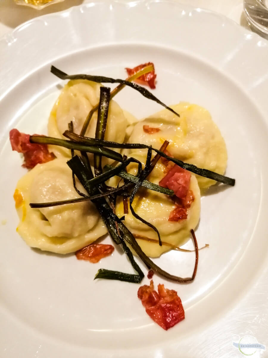 Mit Käse gefüllte Tortellini, garniert mit Lauch und Speck