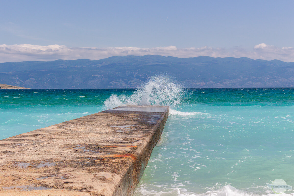 Betonsteg ins Meer mit Welle