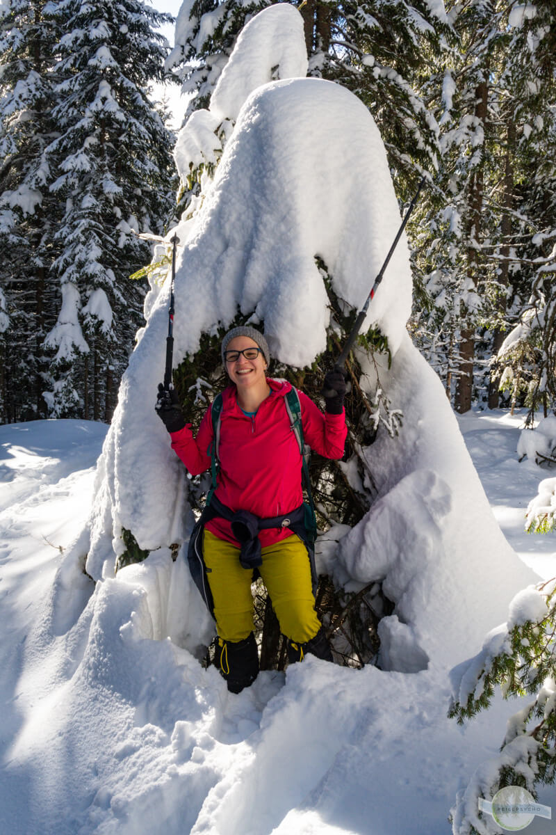Beim Wandern im Winter unter einem Baum mit Schnee stehend