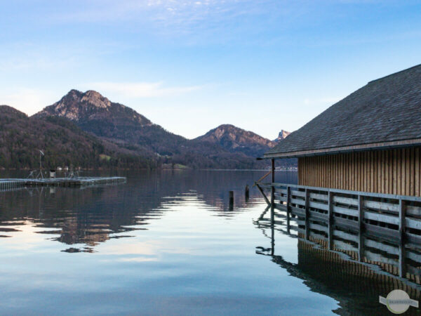 Fuschlsee im Winter - ruhender See mit Hütte und Bergen
