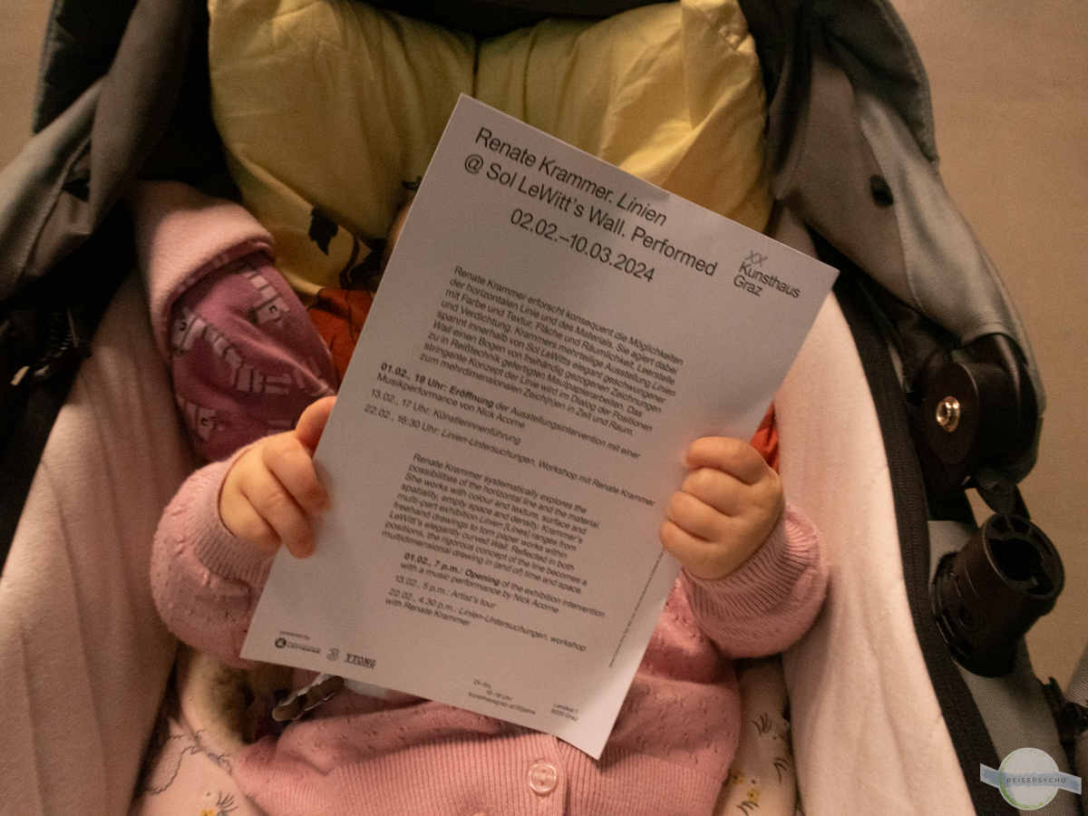 Baby mit Zettel zu dem Kunstwerk im Museum