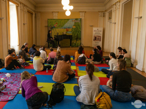 Konzert für Eltern und Babys in Wien - Saal mit sitzenden Müttern und Babys auf Matten