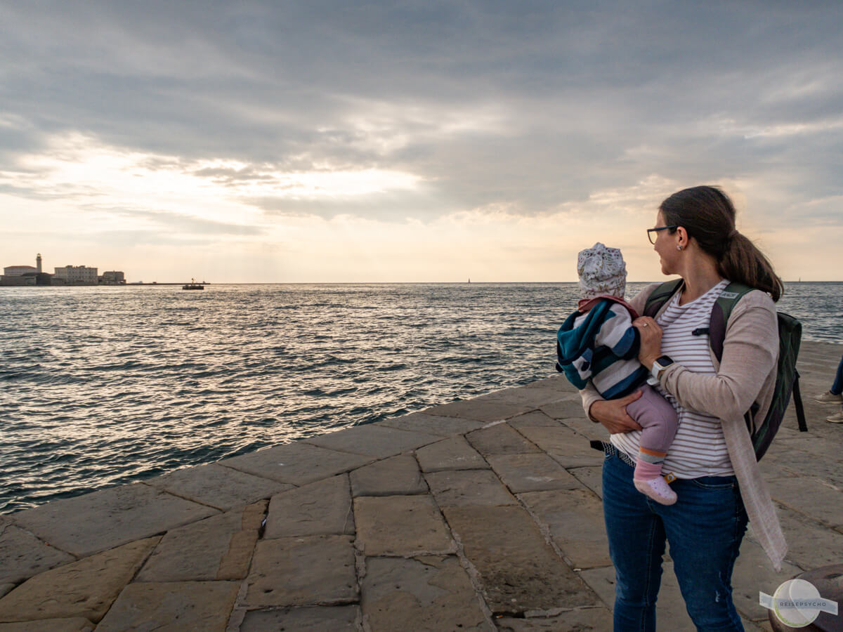Mit Baby auf der Mole in Triest aufs Meer schauen