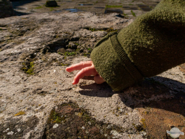 Babyhände auf einem alten Stein