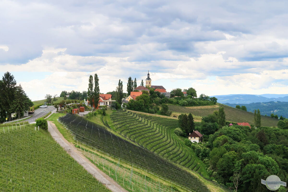 Kitzeck: Die Kirche, die Straße mit den Pappeln und an ihren Flanken die Weinberge
