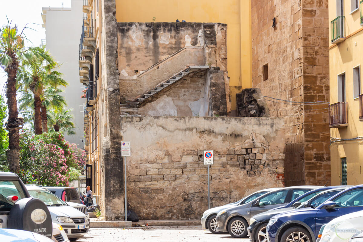 Trapani halbes Haus, Stiege sichtbar, davor stehen Autos am Parkplatz